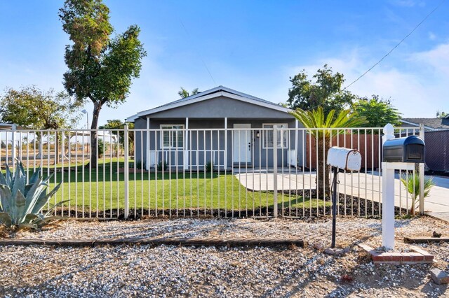 view of front of home with stucco siding, fence, and a front yard