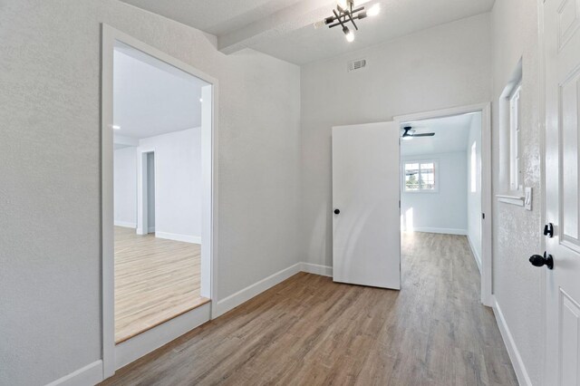 empty room with light wood-style floors, visible vents, and baseboards