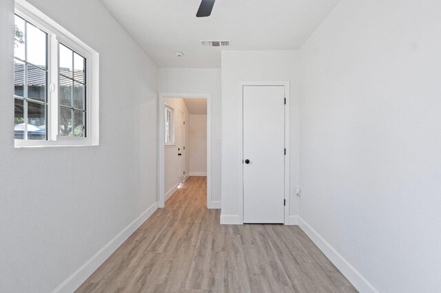 unfurnished bedroom with light wood-style flooring, a ceiling fan, visible vents, and baseboards