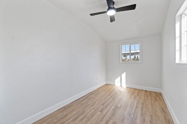 spare room featuring light wood-type flooring, baseboards, vaulted ceiling, and a ceiling fan