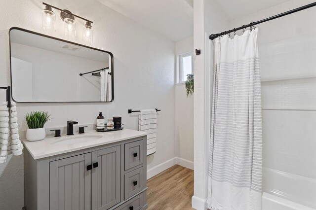 bathroom with shower / bath combo with shower curtain, wood finished floors, vanity, and baseboards