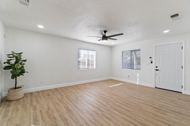 interior space with baseboards, a ceiling fan, visible vents, and light wood-style floors