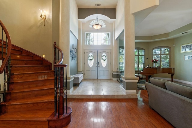 foyer entrance with french doors, light hardwood / wood-style flooring, a high ceiling, and plenty of natural light