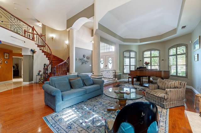 living room featuring decorative columns, a raised ceiling, and hardwood / wood-style flooring