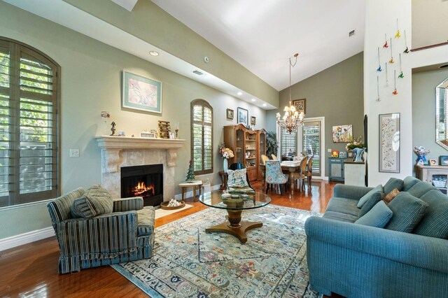 living room featuring hardwood / wood-style floors, a healthy amount of sunlight, a fireplace, and an inviting chandelier