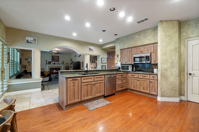 kitchen with sink, ceiling fan, light wood-type flooring, kitchen peninsula, and stainless steel appliances