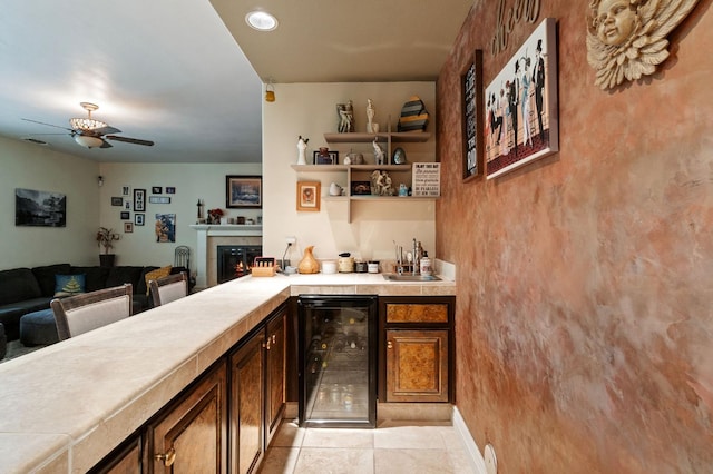 bar featuring ceiling fan, sink, a tile fireplace, light tile patterned floors, and wine cooler