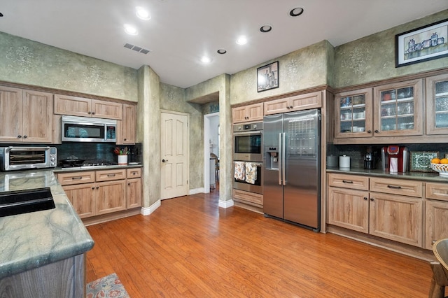 kitchen featuring sink, light wood-type flooring, stainless steel appliances, and stone counters