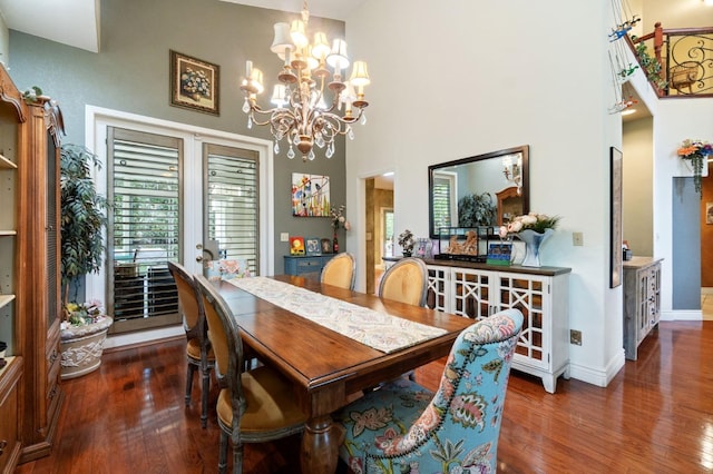 dining space with a towering ceiling, dark hardwood / wood-style floors, and a notable chandelier