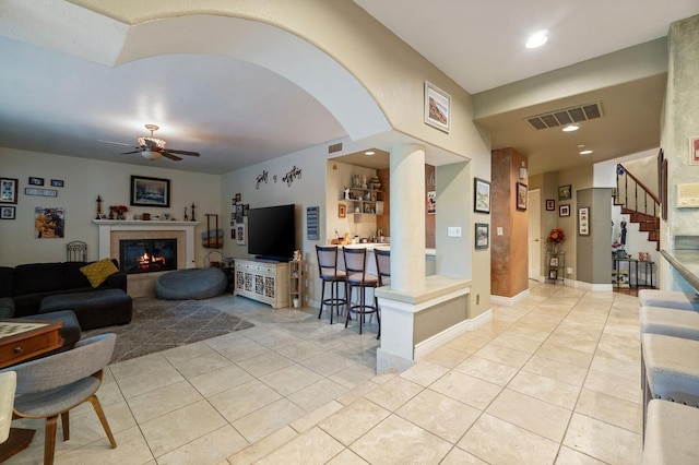 tiled living room featuring a tile fireplace and ceiling fan