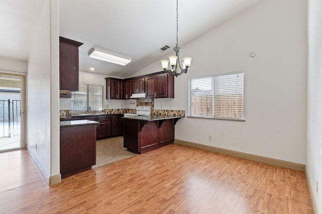 kitchen featuring light wood-type flooring, plenty of natural light, white range oven, and a breakfast bar