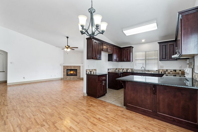 kitchen featuring white range, pendant lighting, vaulted ceiling, light hardwood / wood-style floors, and ceiling fan with notable chandelier