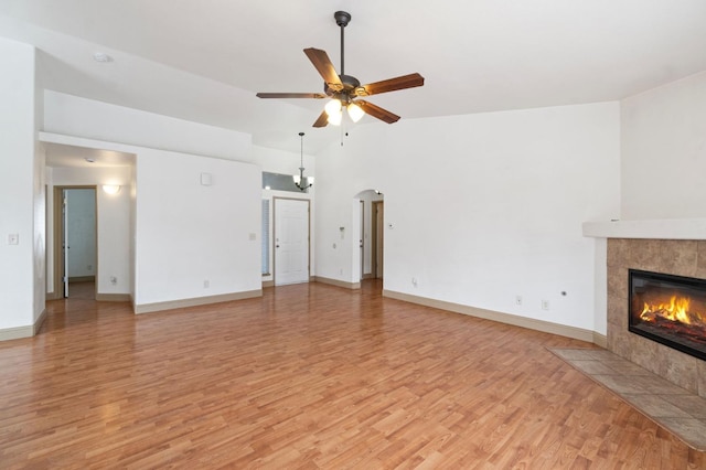 unfurnished living room with a tiled fireplace, high vaulted ceiling, light hardwood / wood-style floors, and ceiling fan