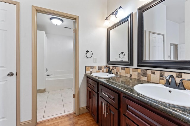 bathroom with hardwood / wood-style floors, vanity, a bathtub, and backsplash