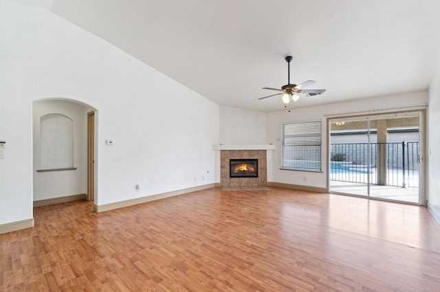 unfurnished living room featuring light hardwood / wood-style flooring, ceiling fan, vaulted ceiling, and a tile fireplace