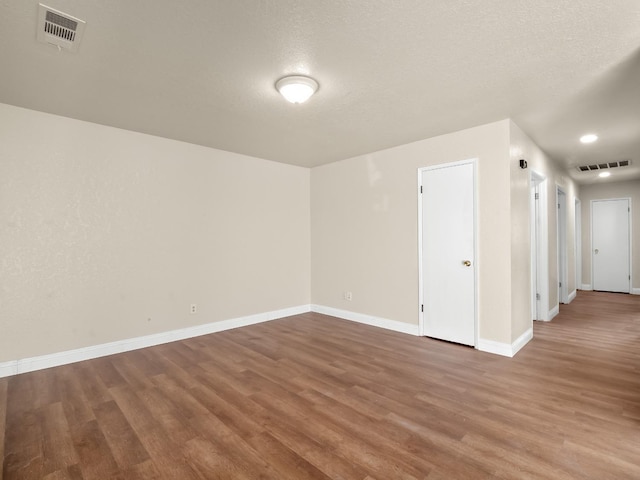 unfurnished room with a textured ceiling and hardwood / wood-style flooring