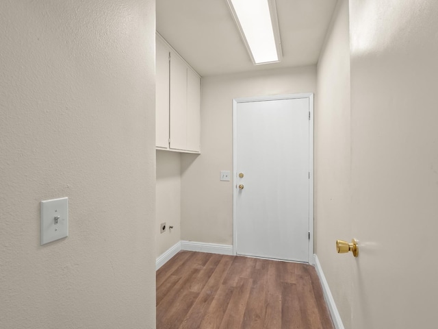 laundry area featuring electric dryer hookup, light wood-type flooring, and cabinets