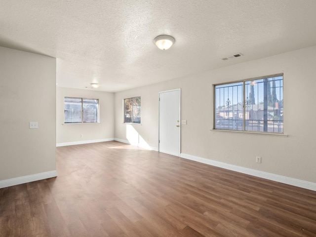 unfurnished living room featuring dark wood-type flooring and a textured ceiling