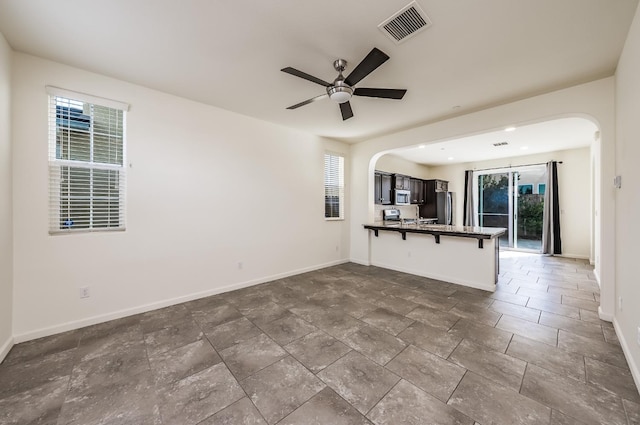 kitchen with kitchen peninsula, a breakfast bar area, ceiling fan, dark brown cabinets, and appliances with stainless steel finishes