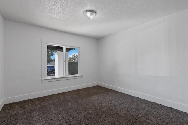 spare room with a textured ceiling and dark carpet