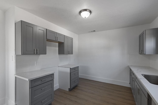 kitchen featuring gray cabinets, a textured ceiling, backsplash, and dark hardwood / wood-style flooring