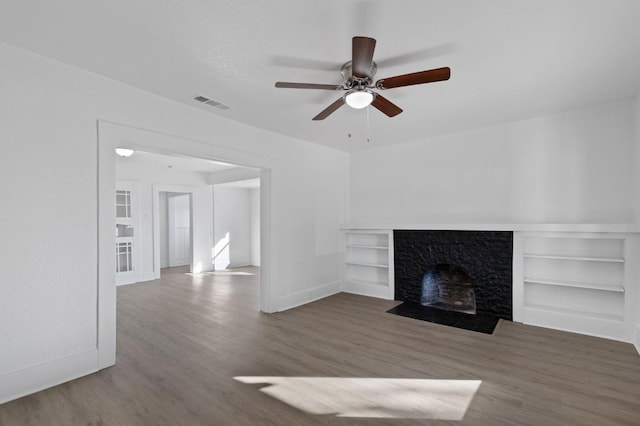 unfurnished living room with hardwood / wood-style floors, a stone fireplace, and ceiling fan