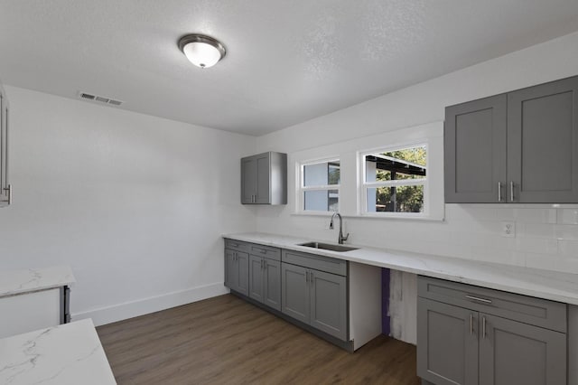 kitchen featuring gray cabinets, dark hardwood / wood-style floors, sink, and light stone counters