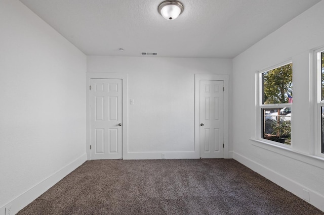 empty room with a textured ceiling and carpet floors