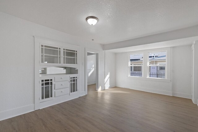 unfurnished living room featuring wood-type flooring and a textured ceiling