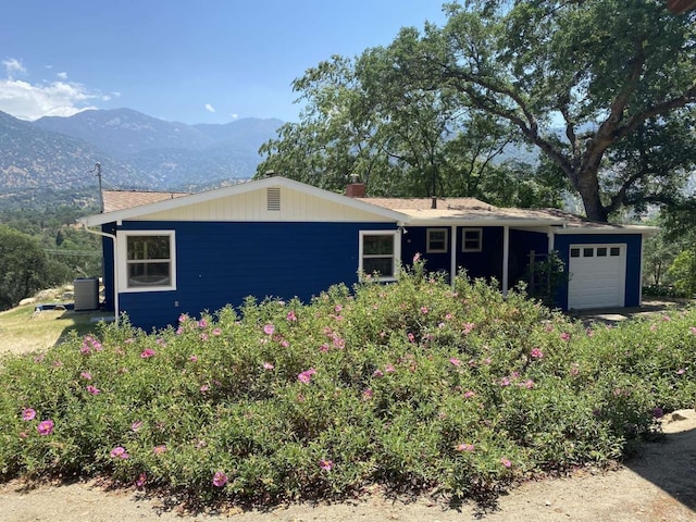 single story home featuring a mountain view, a garage, and cooling unit