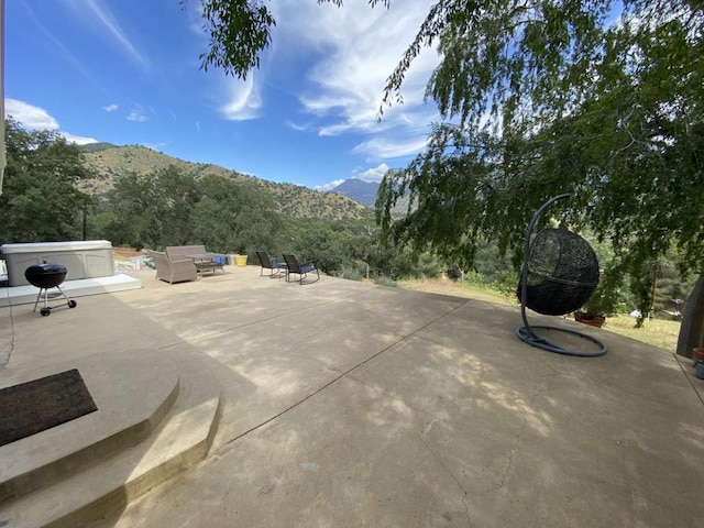 view of patio / terrace with a mountain view, a hot tub, and an outdoor hangout area