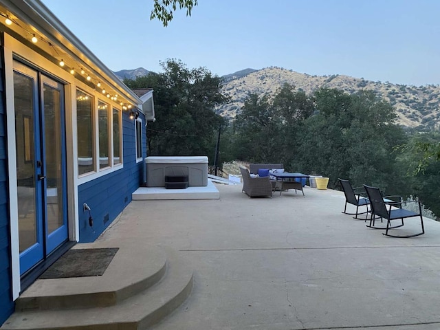 view of patio / terrace featuring a hot tub and a mountain view