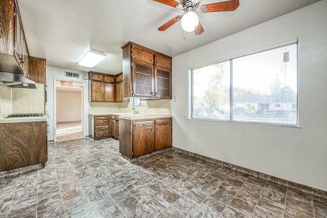 kitchen featuring extractor fan, backsplash, sink, stainless steel gas cooktop, and ceiling fan