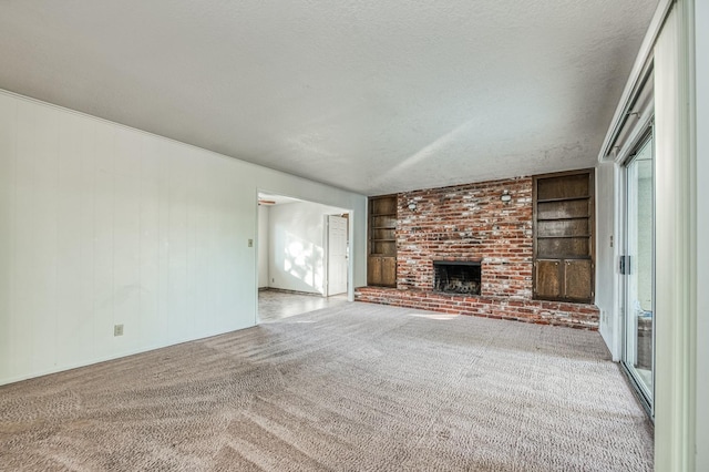 unfurnished living room featuring a fireplace, light colored carpet, a textured ceiling, and built in shelves