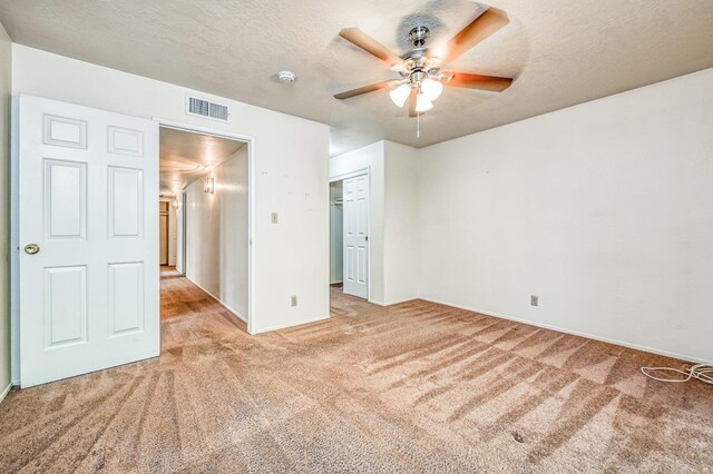 unfurnished bedroom with a closet, a textured ceiling, light colored carpet, and ceiling fan