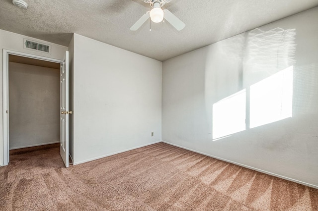 spare room featuring a textured ceiling, carpet, and ceiling fan