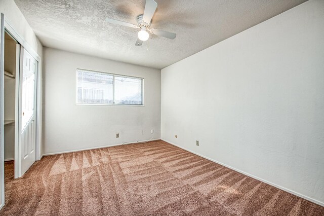 unfurnished bedroom featuring ceiling fan, a textured ceiling, and carpet