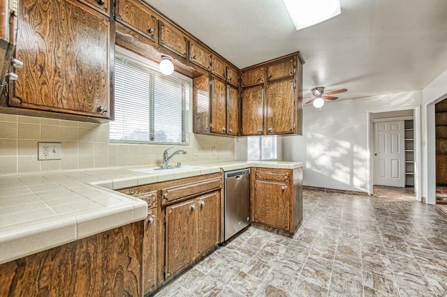 kitchen with sink, ceiling fan, backsplash, tile counters, and dishwasher