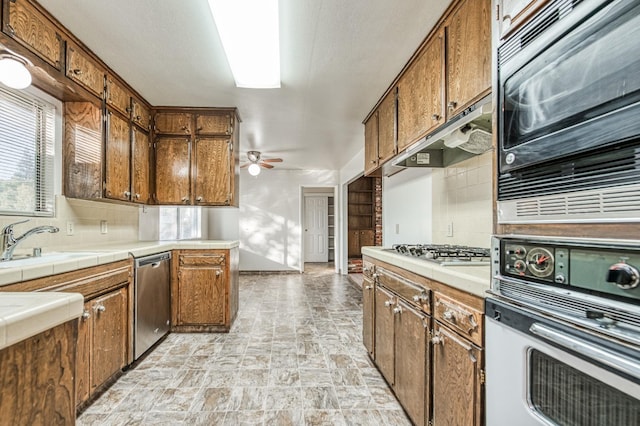 kitchen featuring stainless steel appliances, ceiling fan, tasteful backsplash, and plenty of natural light