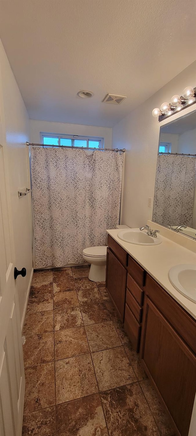 bathroom featuring toilet, vanity, and a textured ceiling