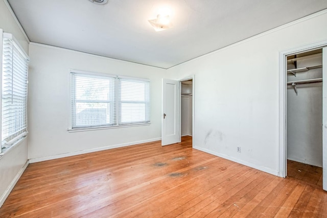 unfurnished bedroom featuring a closet, a walk in closet, and light hardwood / wood-style flooring