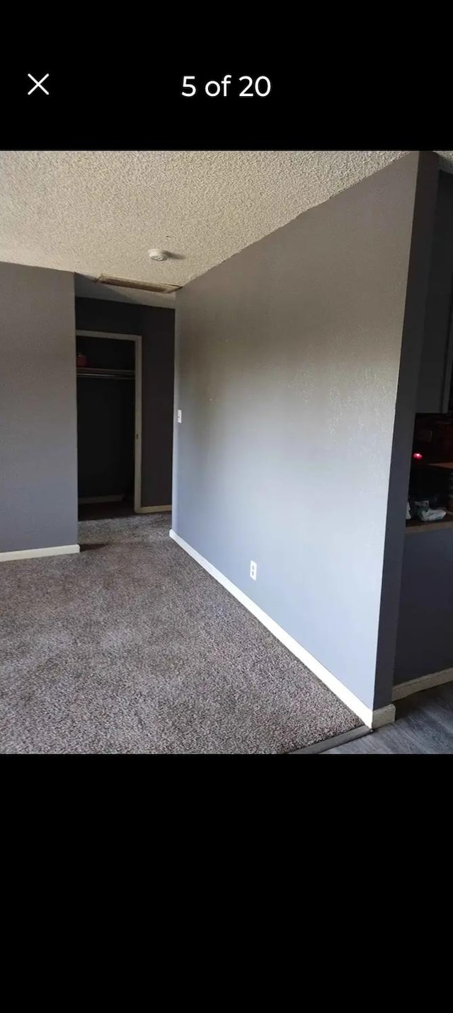 unfurnished room with a textured ceiling and carpet floors