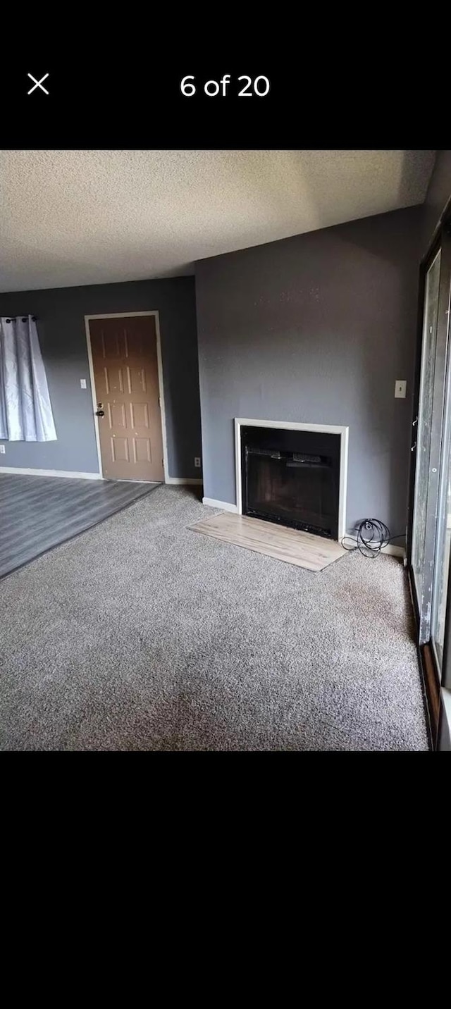 unfurnished living room featuring a textured ceiling and carpet flooring