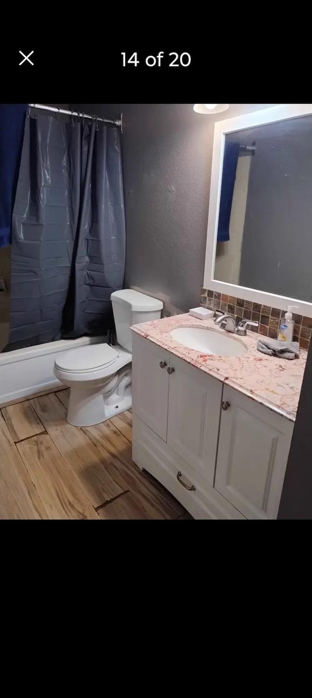 full bathroom with shower / bath combo, wood-type flooring, toilet, and vanity