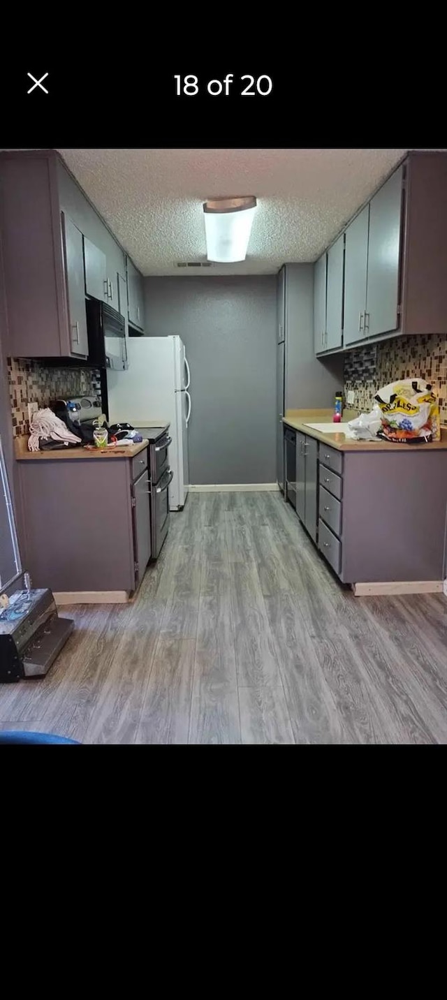 kitchen featuring gray cabinets, backsplash, a textured ceiling, and light hardwood / wood-style floors