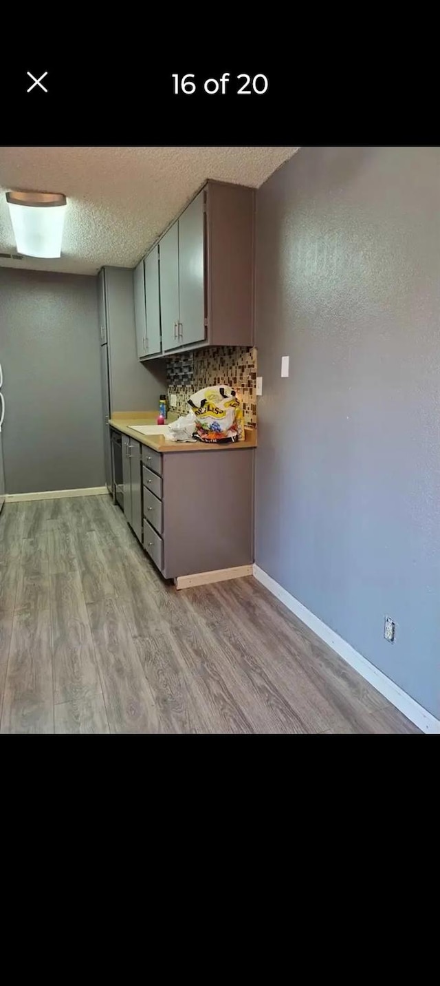 kitchen with decorative backsplash, light hardwood / wood-style floors, and a textured ceiling