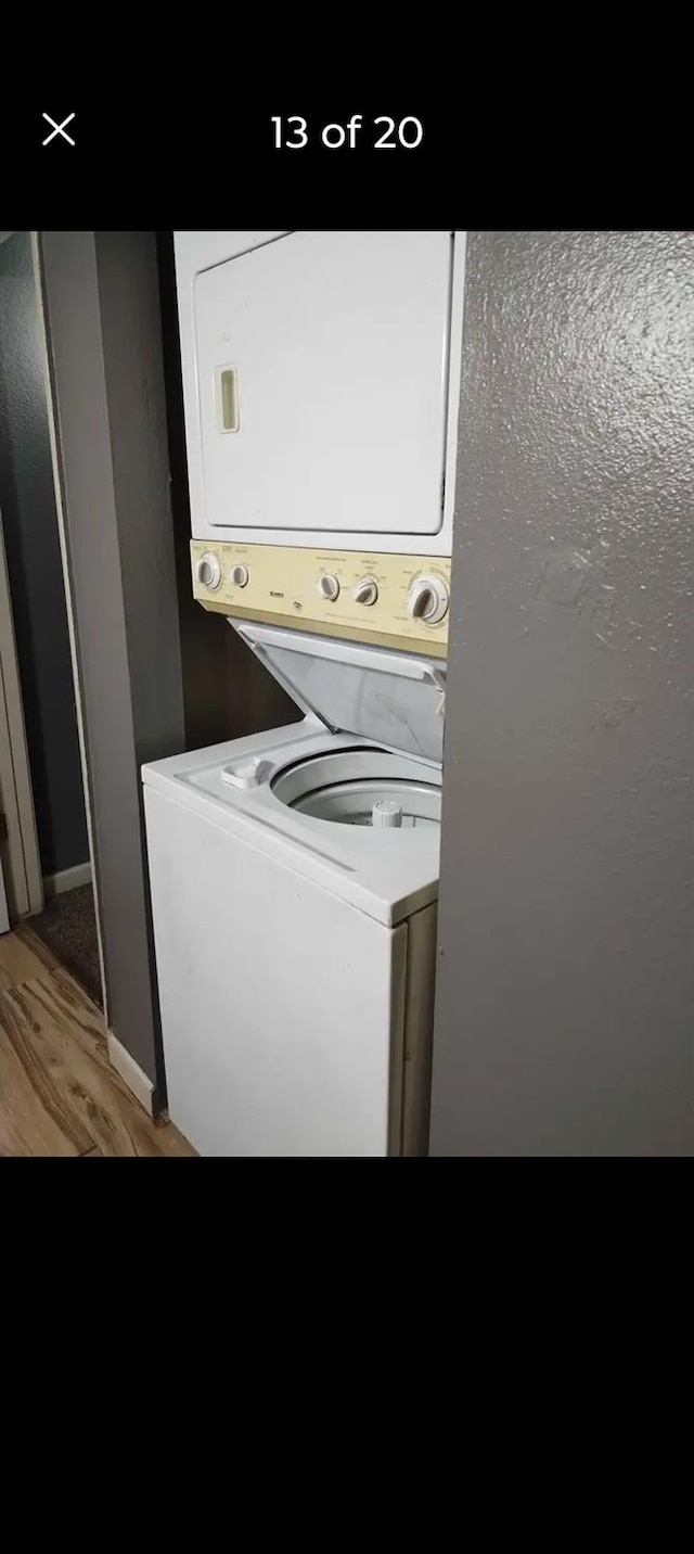 clothes washing area with hardwood / wood-style floors and stacked washer and clothes dryer