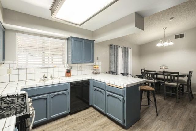 kitchen with tile counters, dishwasher, tasteful backsplash, kitchen peninsula, and decorative light fixtures