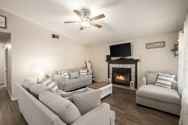 living room with a tile fireplace, vaulted ceiling, ceiling fan, a textured ceiling, and dark hardwood / wood-style flooring