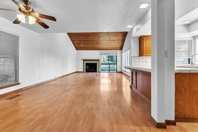 unfurnished living room with light hardwood / wood-style floors, lofted ceiling, and a textured ceiling